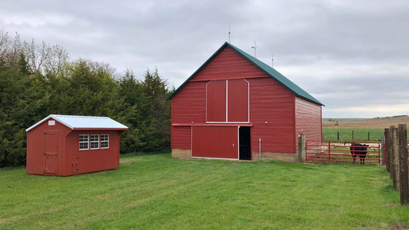 Chicken Coop across from big red barn with green roof on cloudy day