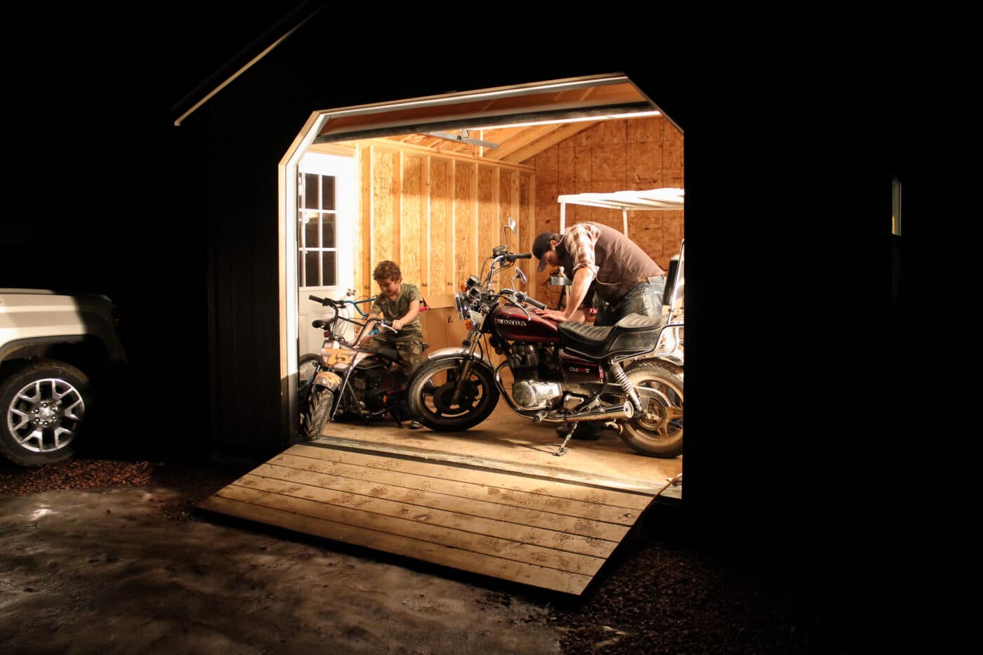 Man and boy working on motorcycle in detached A-Frame Garage