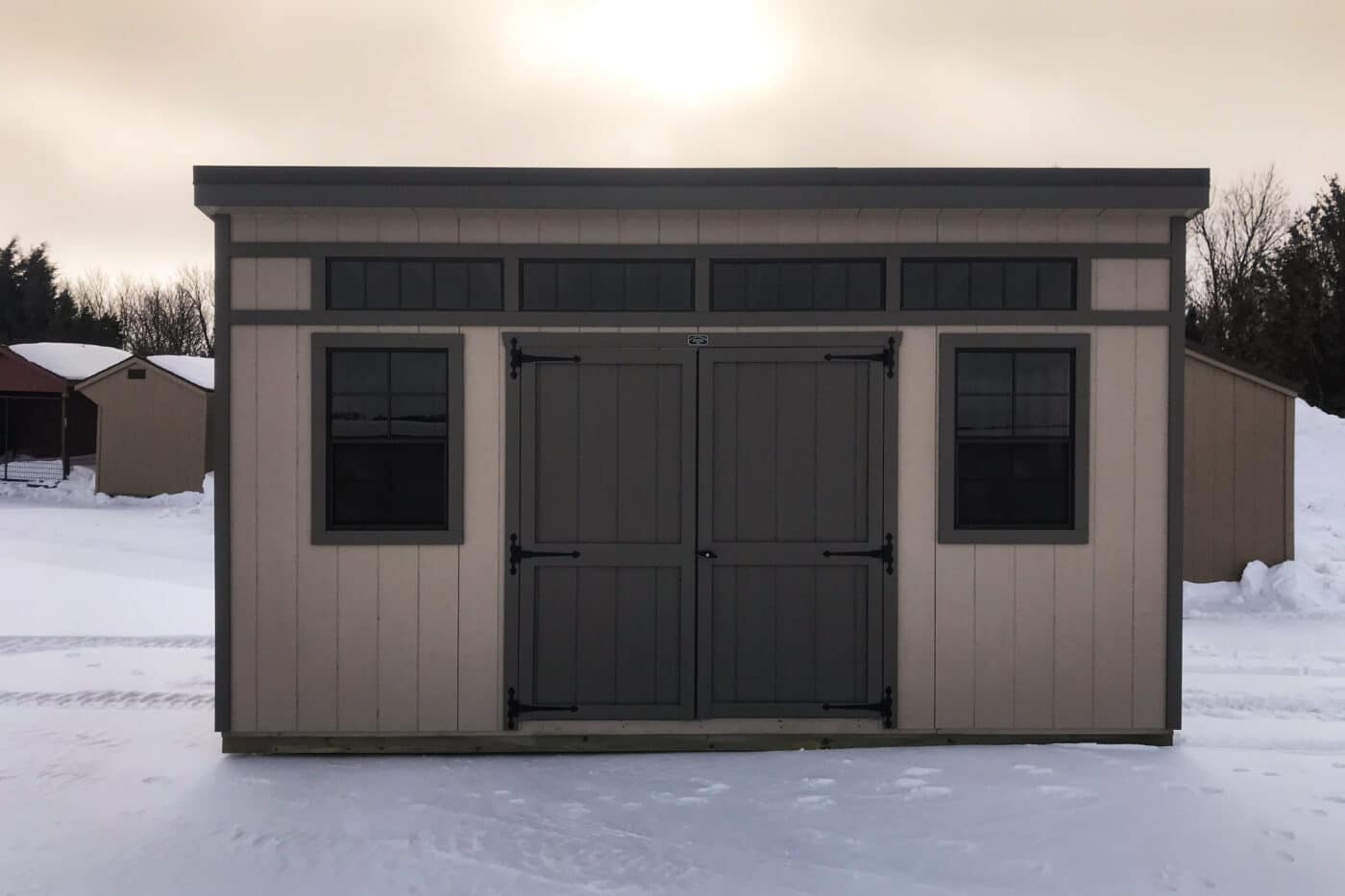 tan & black trim modern studio shed in snow