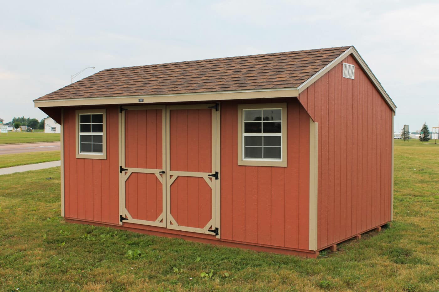 Storage shed with orange siding, shingle roof, and an overhang