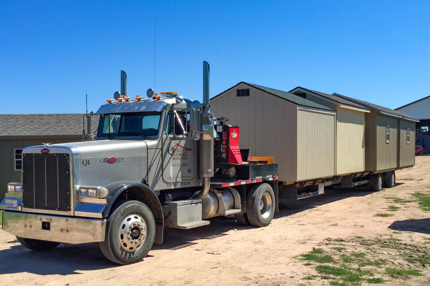 Tractor trailer delivering storage sheds